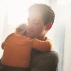 Man holding sleeping daughter as sunlight streams in from window