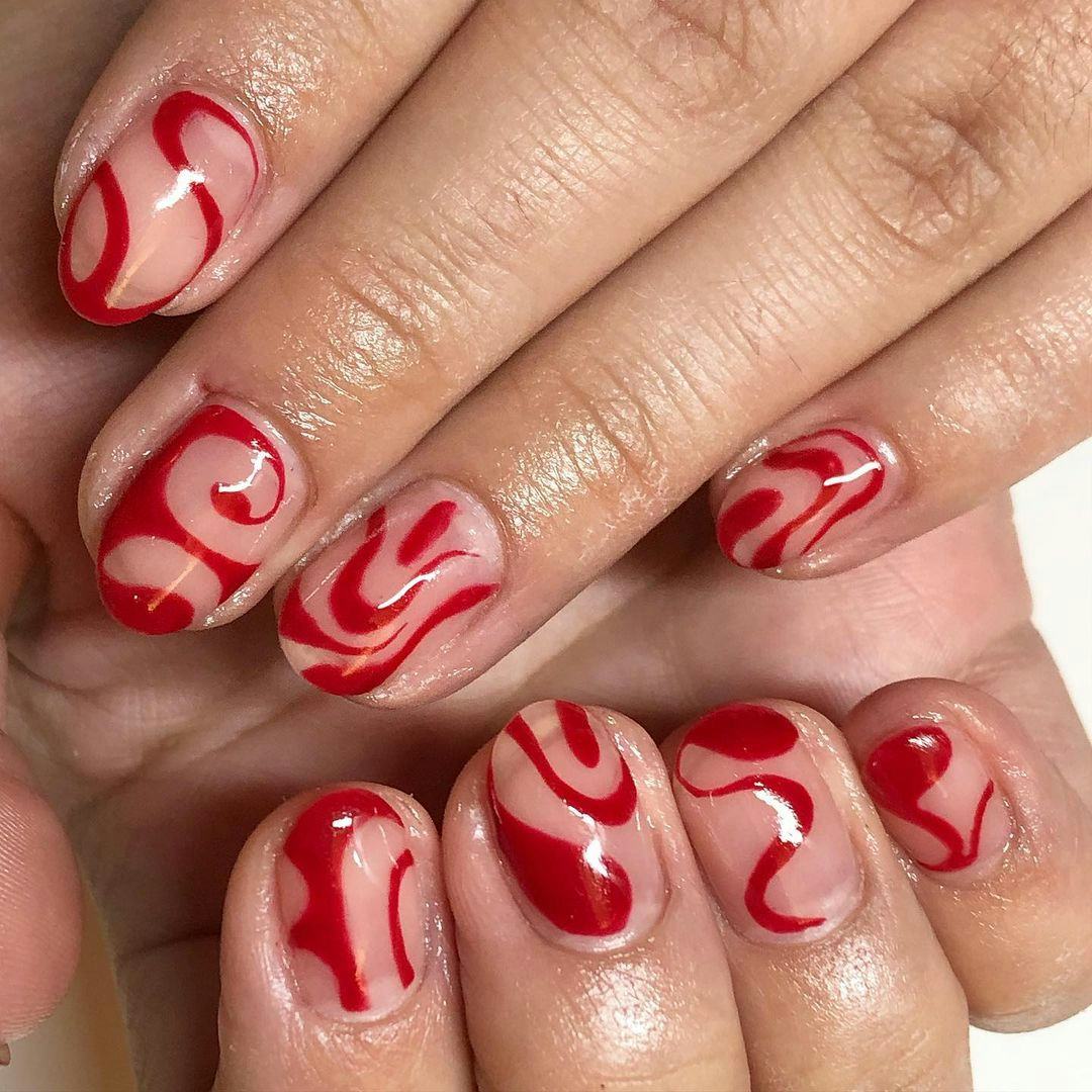 An abstract red swirl nail art design that nods to Taylor Swift&rsquo;s signature red lipstick.
