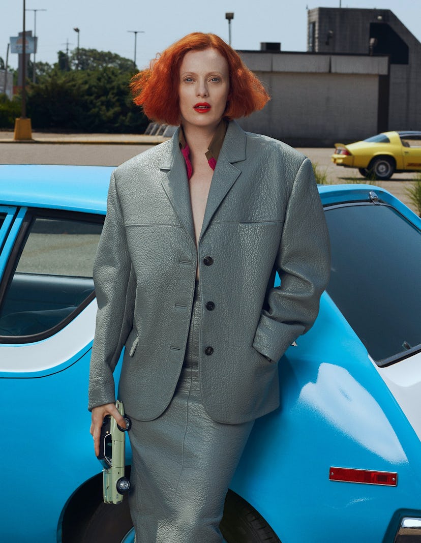 the model Karen Elson wears a leather outfit while reclining against a vintage car