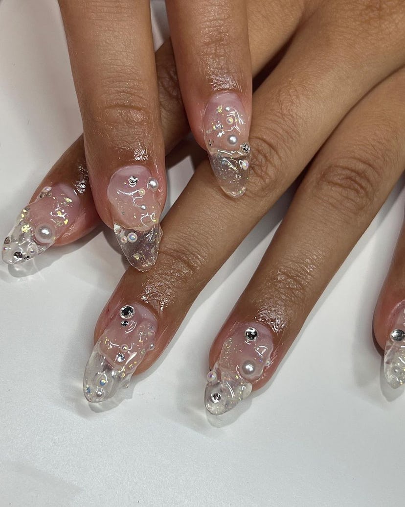 Almond-shaped, medium-length clear nails with 3D texture and pearls.