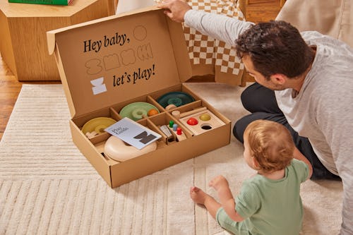 Lifestyle shot of baby and dad opening up Lalo's The Play Box, their new subscription toy box 