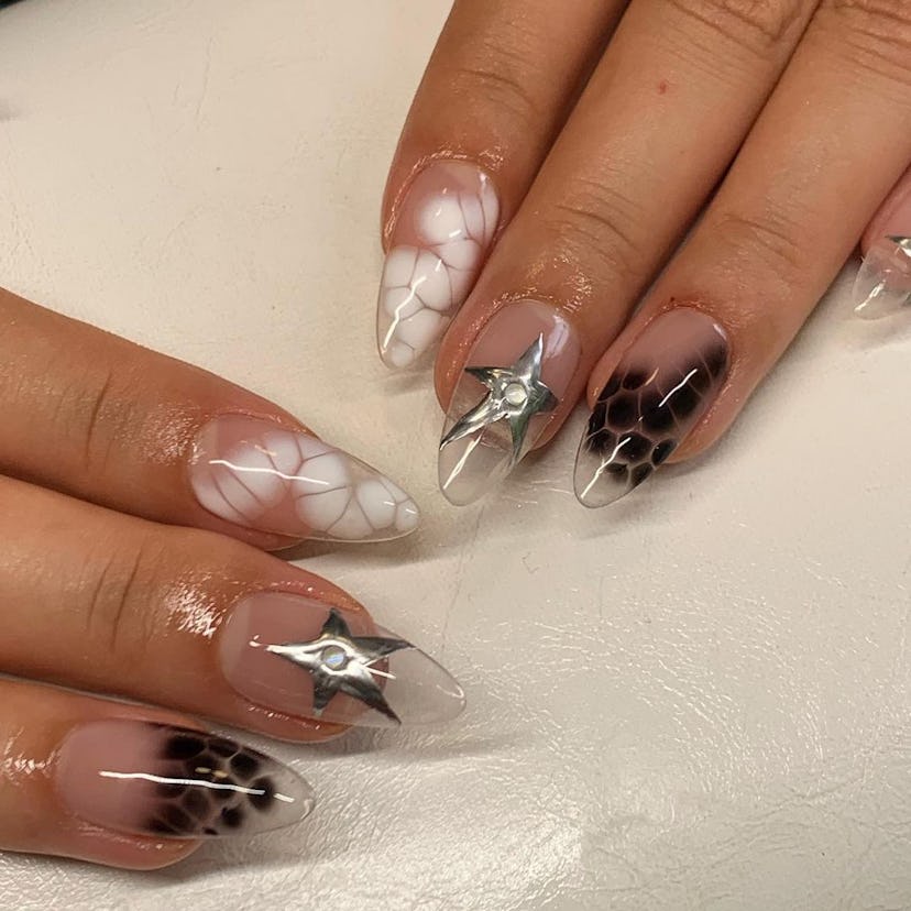 A black, white, & chrome silver nail art design on clear, almond-shaped acrylic nails.