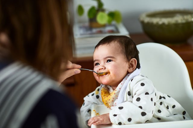 A mother spoonfeeds her hungry baby.