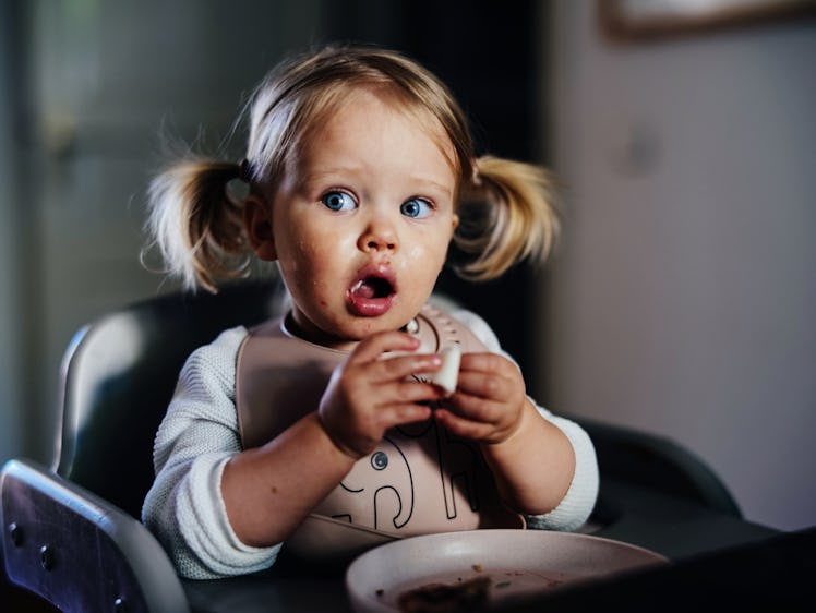 A toddler eating in a high chair.