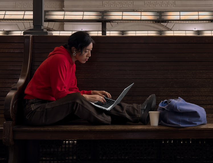 A person using an Apple 14-inch MacBook Pro with M3 chip on a bench at train station