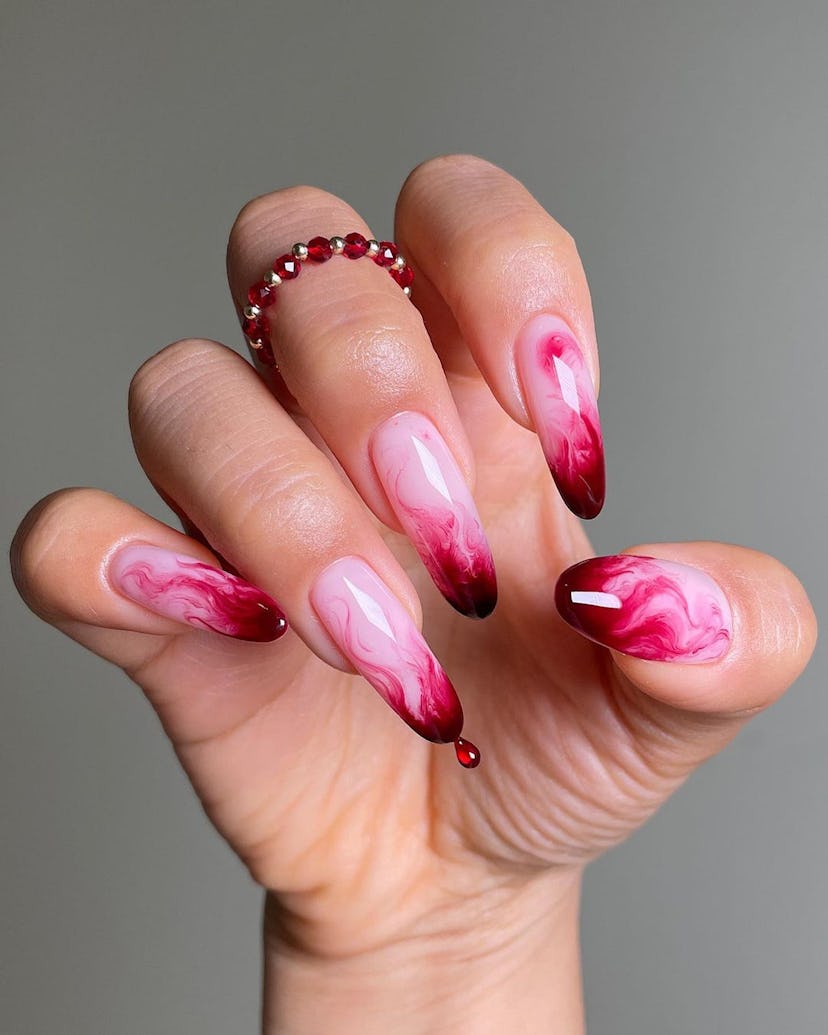 A red blood splatter manicure is a trendy design idea for vampire nails this Halloween 2023.