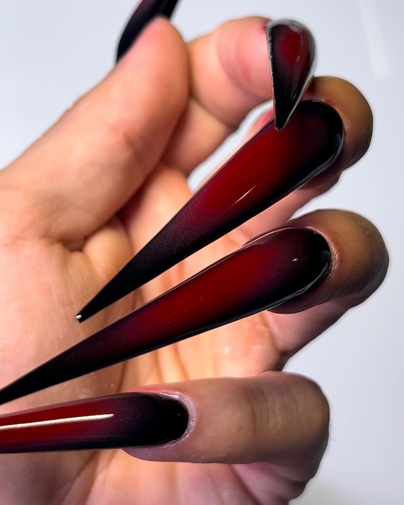 Trendy black & red vampire nails with long stiletto-shaped tips.