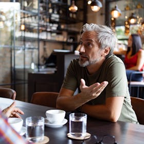 middle aged man venting to his friend at a bar