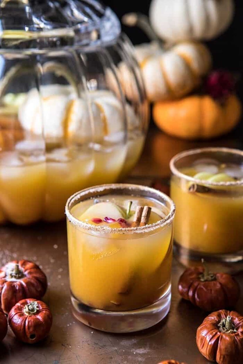 Halloween mocktail punch in a rocks glass with apples and cinnamon sticks inside.