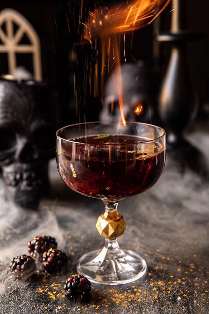 Easy Halloween cocktail called the goblet of fire, red drink in a coupe glass with embers coming out...