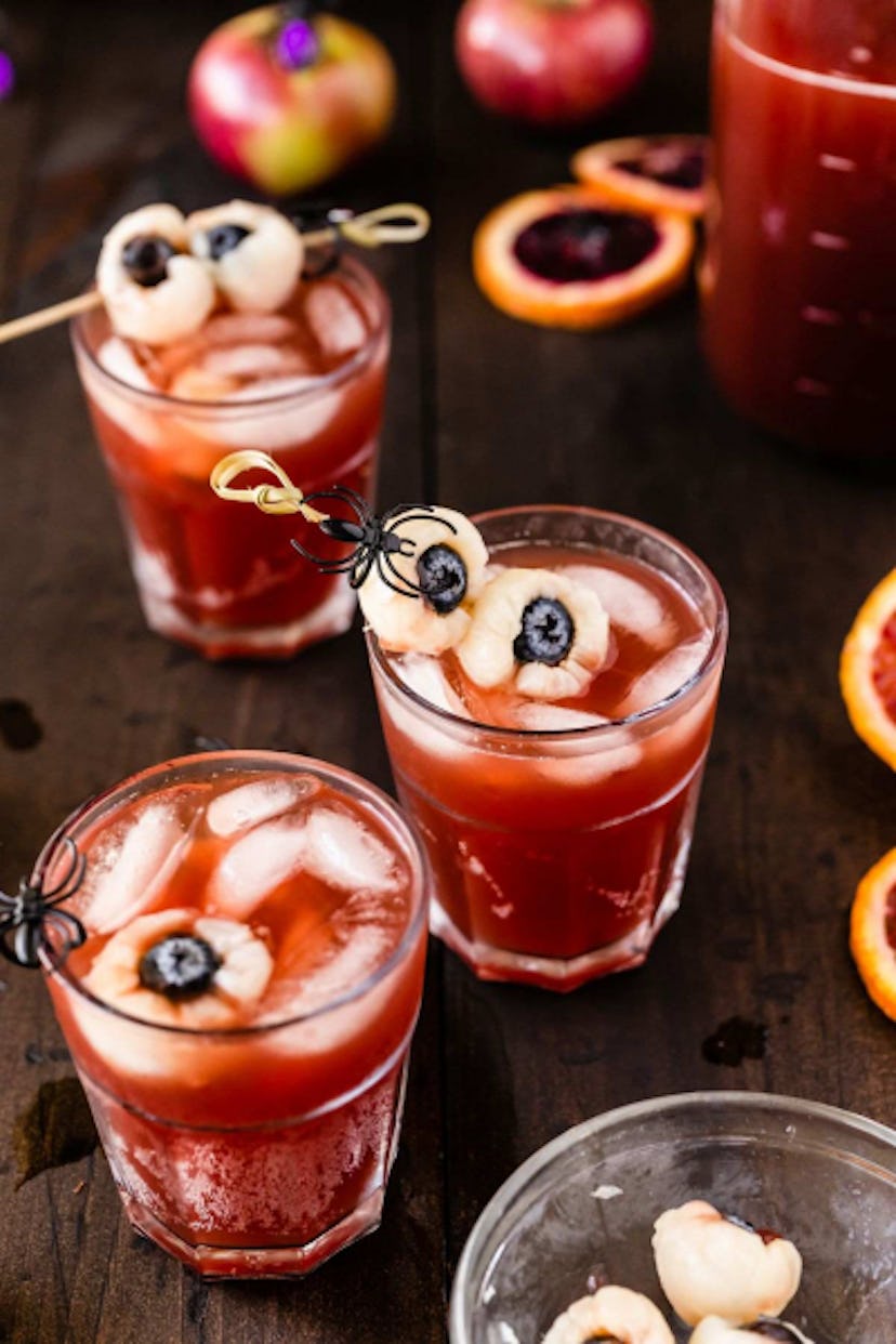 Red Halloween mocktail punch in glasses with ice and rambutan eyeball garnishes.