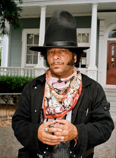 Boots Riley wears a wool hat, silk scarf, black jacket and ring.