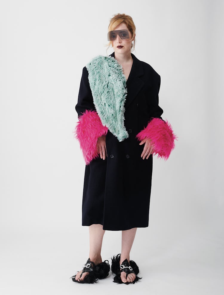 Angelica Hicks wears a black wool coat, flip-flop, green fur scarf and sunglasses.
