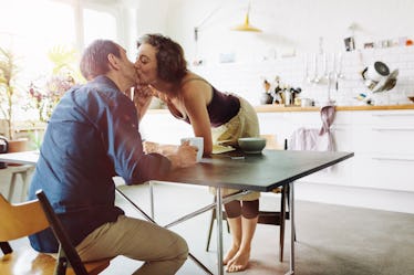 Man and woman kissing at the breakfast table.