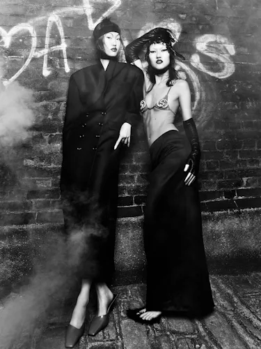 Kim wears a black coat and shoes. Toktorova wears a bra, skirt, gloves, and shoes.