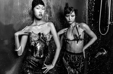 Kim wears a shiny bustier and bracelet. Jia wears a star bra and skirt.