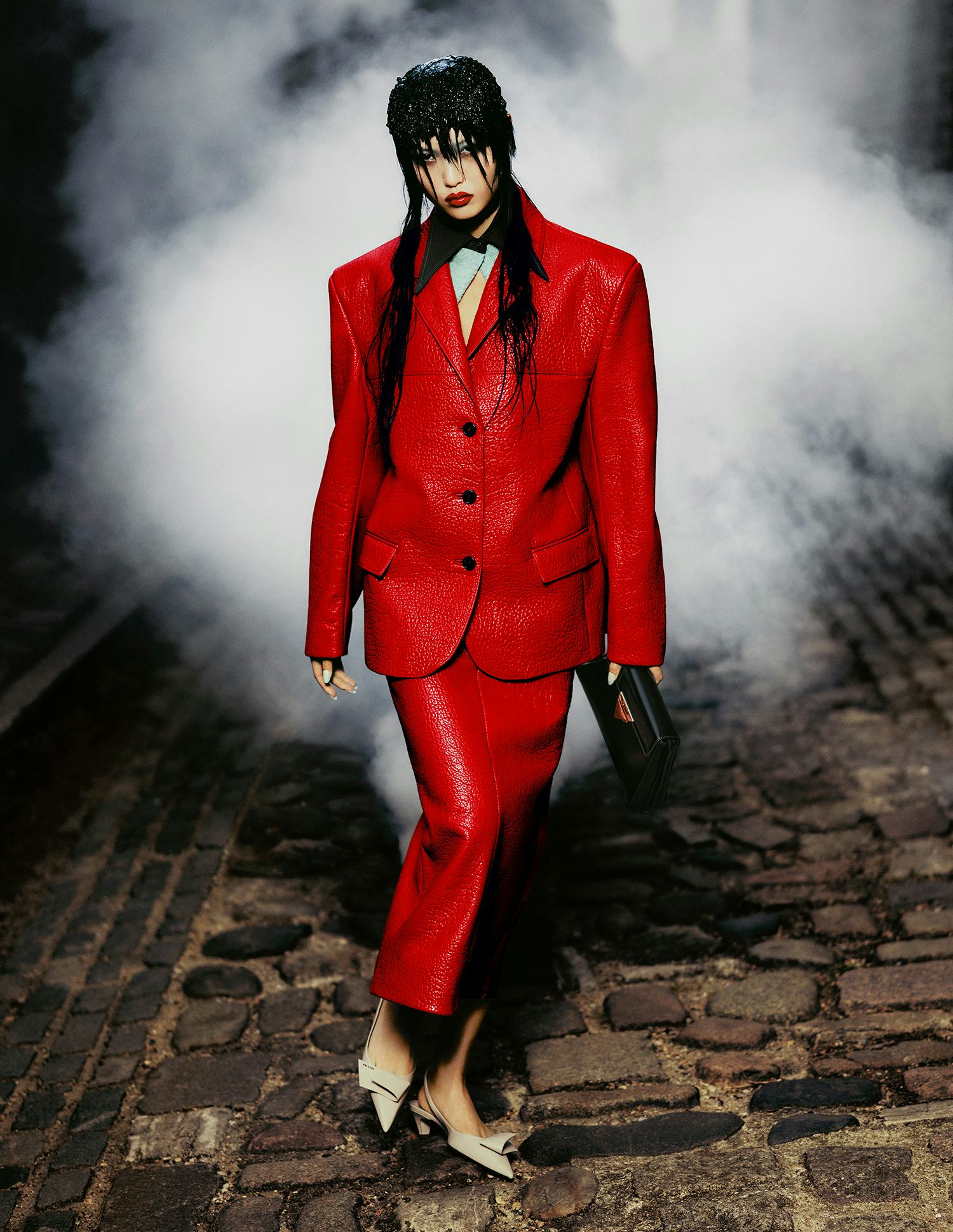Jia wears a red leather blazer, red leather skirt, black clutch bag, and beige shoes.