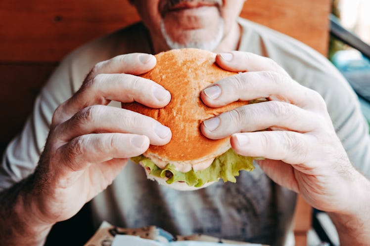 Close up of a man eating a hamburger at a restaurant.