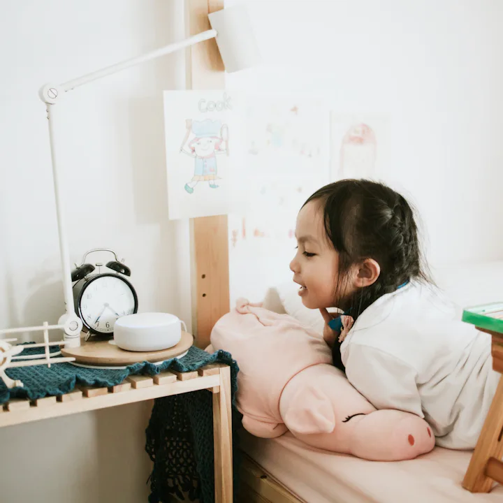 A young girl talks into an AI speaker.