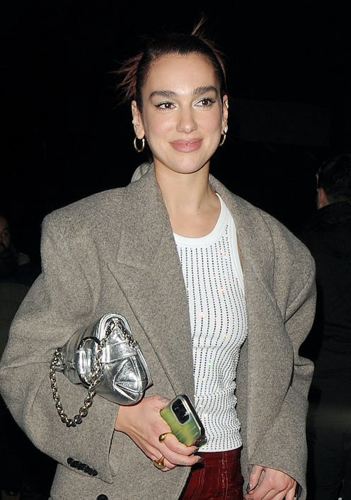 Dua Lipa wears a white tank, burgundy pants, white pumps, and the latest Gucci Horsebit Chain bag.