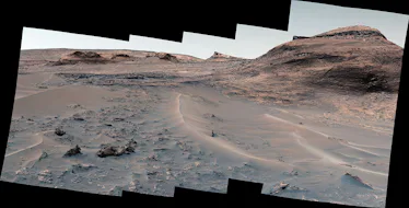 Shallows crests rise from the sand in the foreground. A hill appears on the right, and a flatter ter...