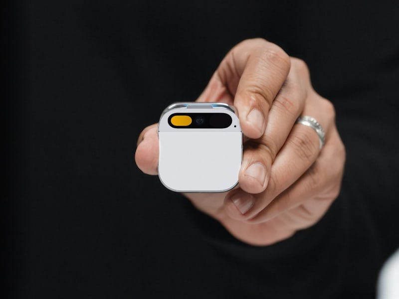 A white and silver Humane Ai Pin in a person's hand