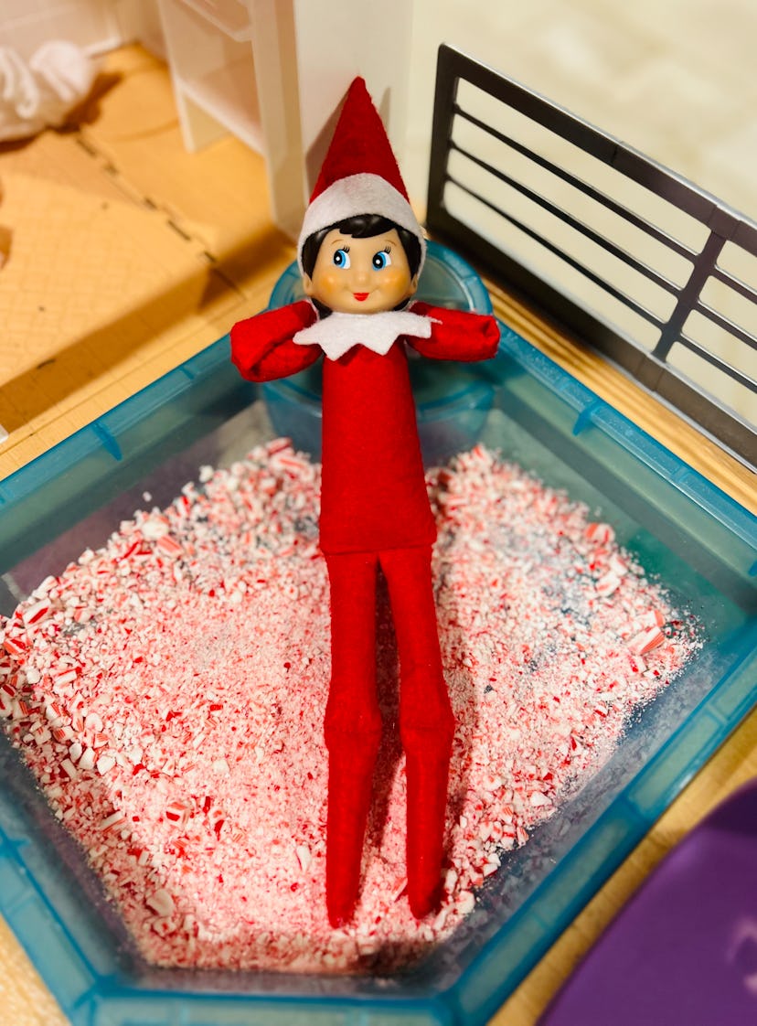 elf on the shelf laying in a Barbie sized pool full of crushed candy cane