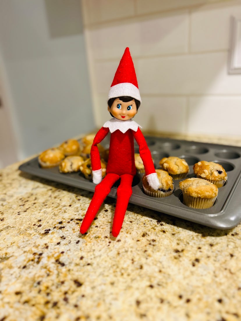 elf on the shelf sitting on a muffin pan