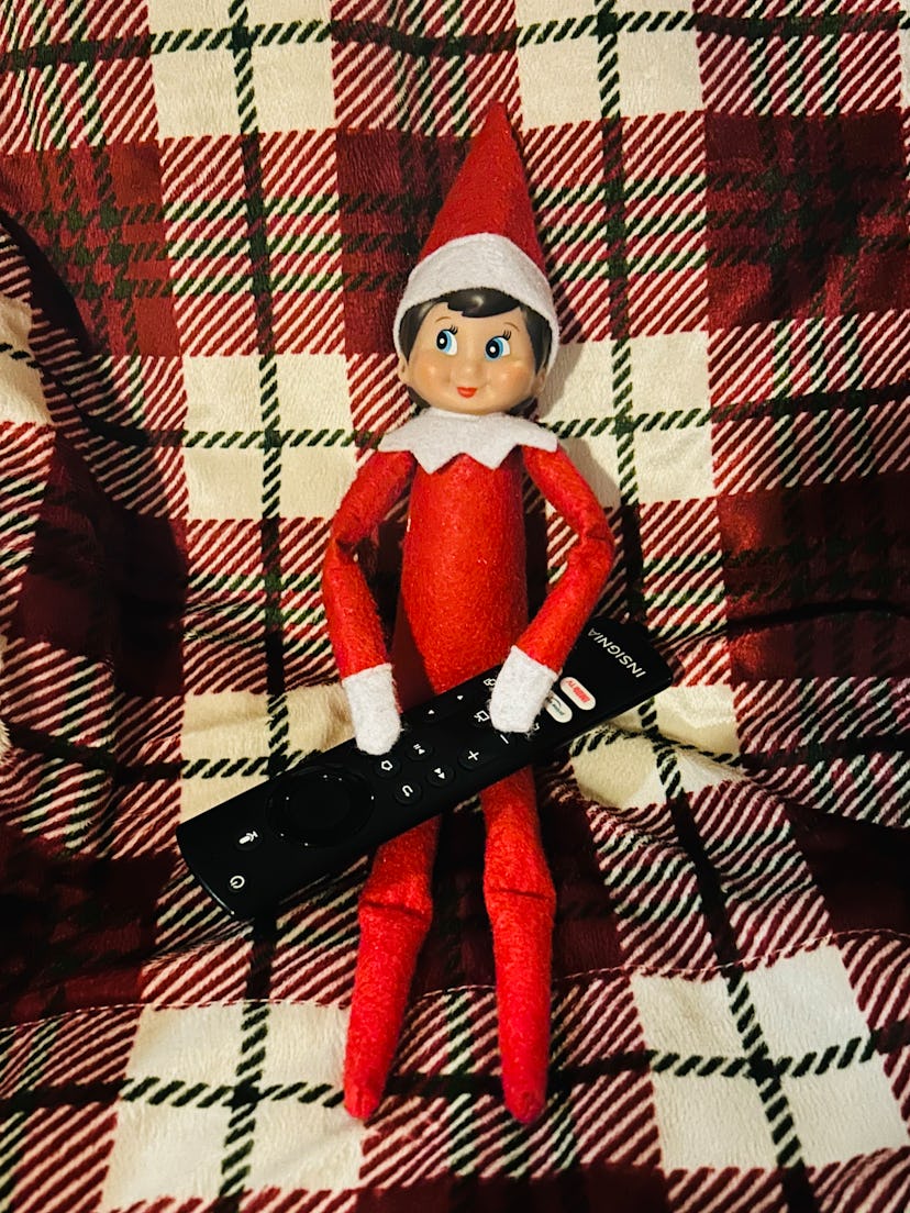 the elf on the shelf holding a tv remote