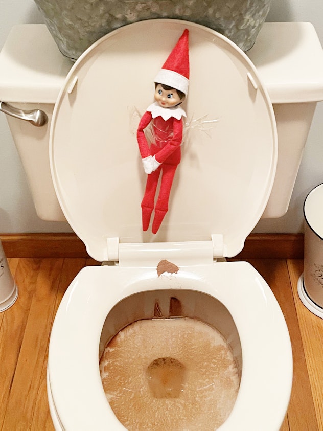 elf on the shelf taped to the inside of the lid of a toilet