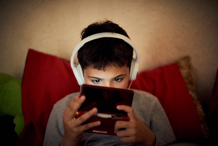 A child with headphones on playing video games on a portable device.