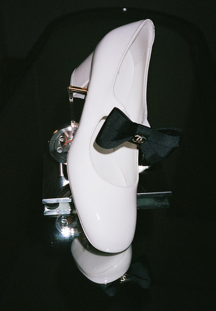 White leather shoes with a black bow.