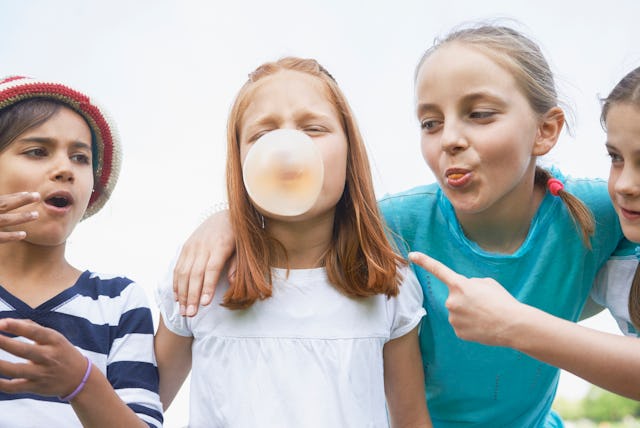 A group of kids blow bubbles with gum.