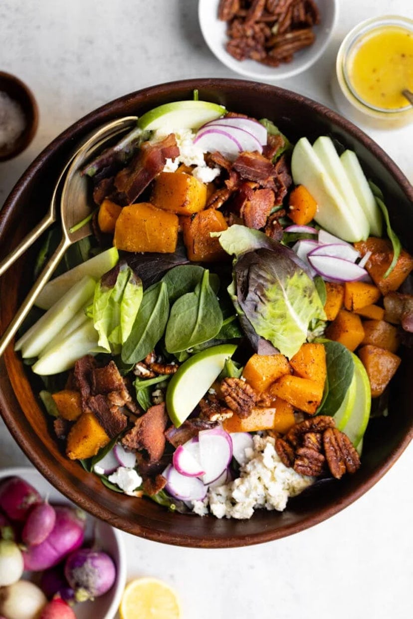 Salad with apples, squash, bacon, and other seasonal ingredients that make it the perfect Thanksgivi...