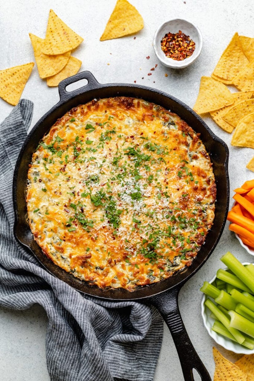 Spinach artichoke dip in a cast iron skillet, a Thanksgiving appetizer guests will love.