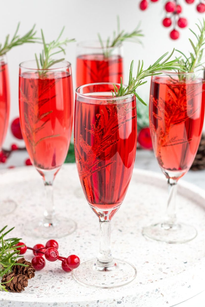 red Christmas mimosas in champagne flutes with christmas garnish