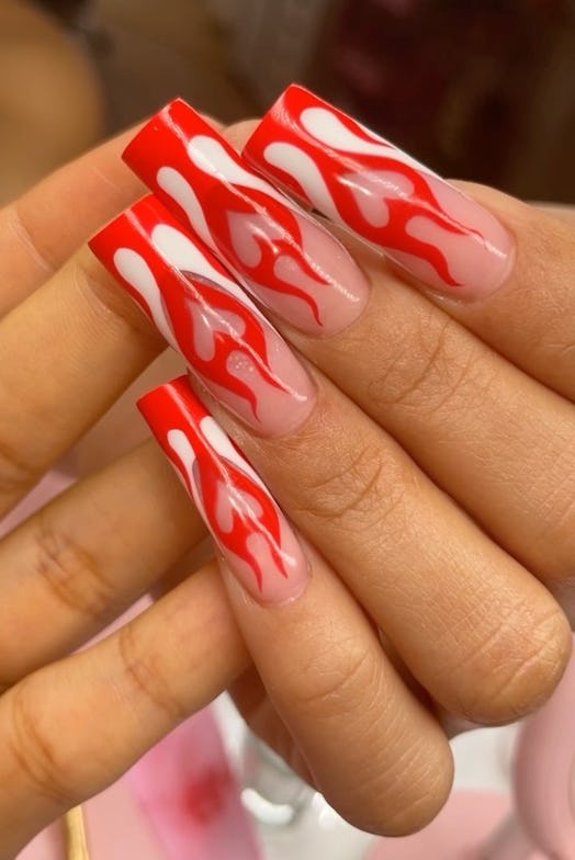 Red-hot flames atop French tip nails are an on-trend nail design for Sagittarius season 2023.