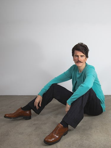 Artist Gillian Wearing wears a green sweater, charcoal pants and brown leather shoes.