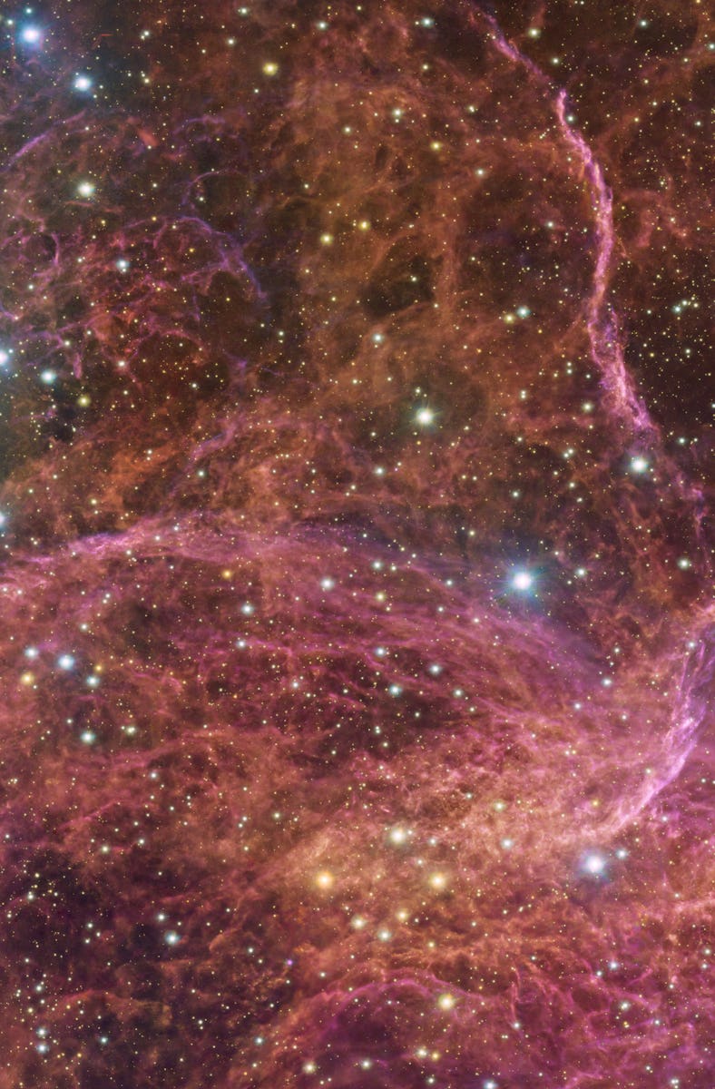 red, orange, and magenta clouds of gas twist and curve against a background of starry sky