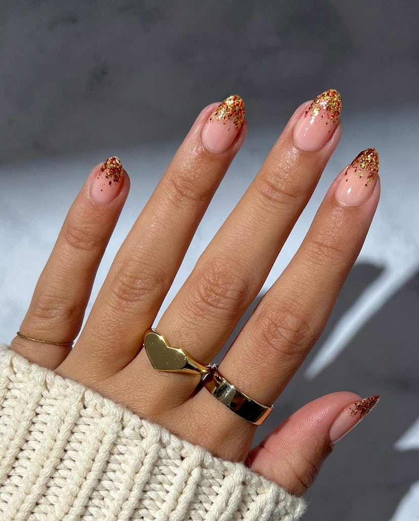 Warm-toned glitter French tip nails are an on-trend manicure design for Sagittarius season 2023.