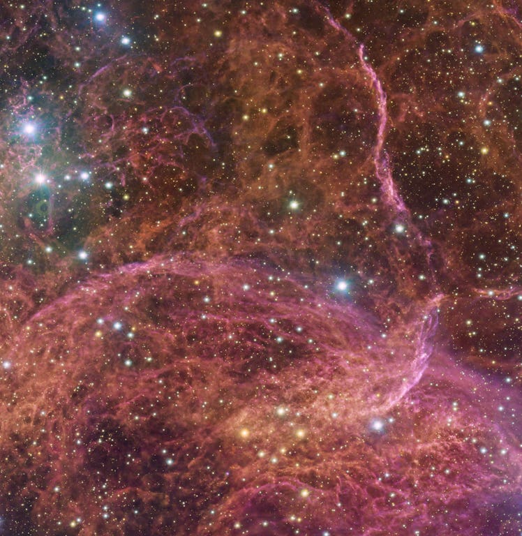 red, orange, and magenta clouds of gas twist and curve against a background of starry sky