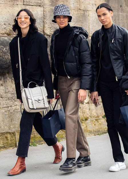 Three models walk along a street carrying shopping bags
