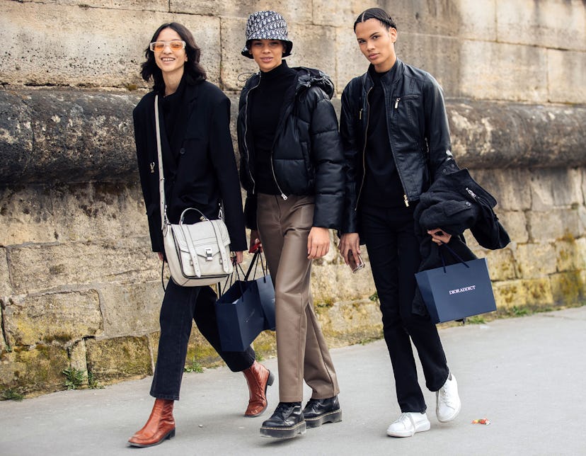 Three models walk along a street carrying shopping bags
