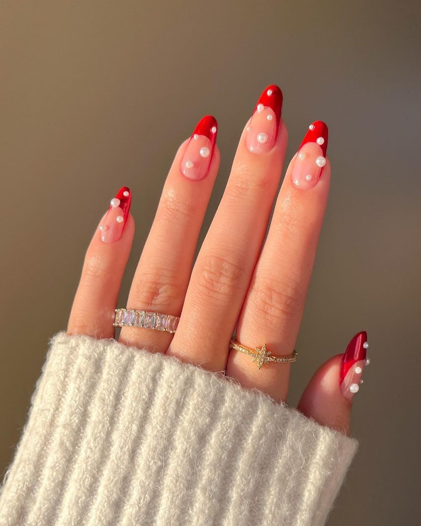 For a simple Christmas nail design for the 2023 holiday season, red French nails and pearls are easy...