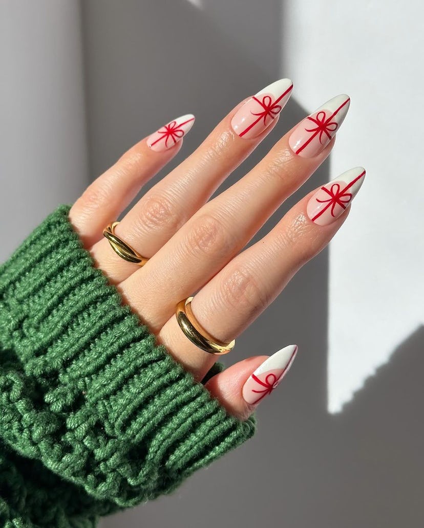 For a simple Christmas nail design for the 2023 holiday season, French nails with red bow nail art a...