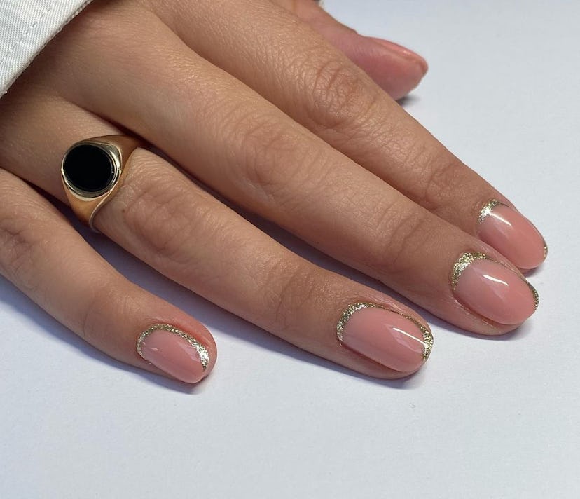 For a simple Christmas nail design for the 2023 holiday season, neutral nails with festive gold glit...