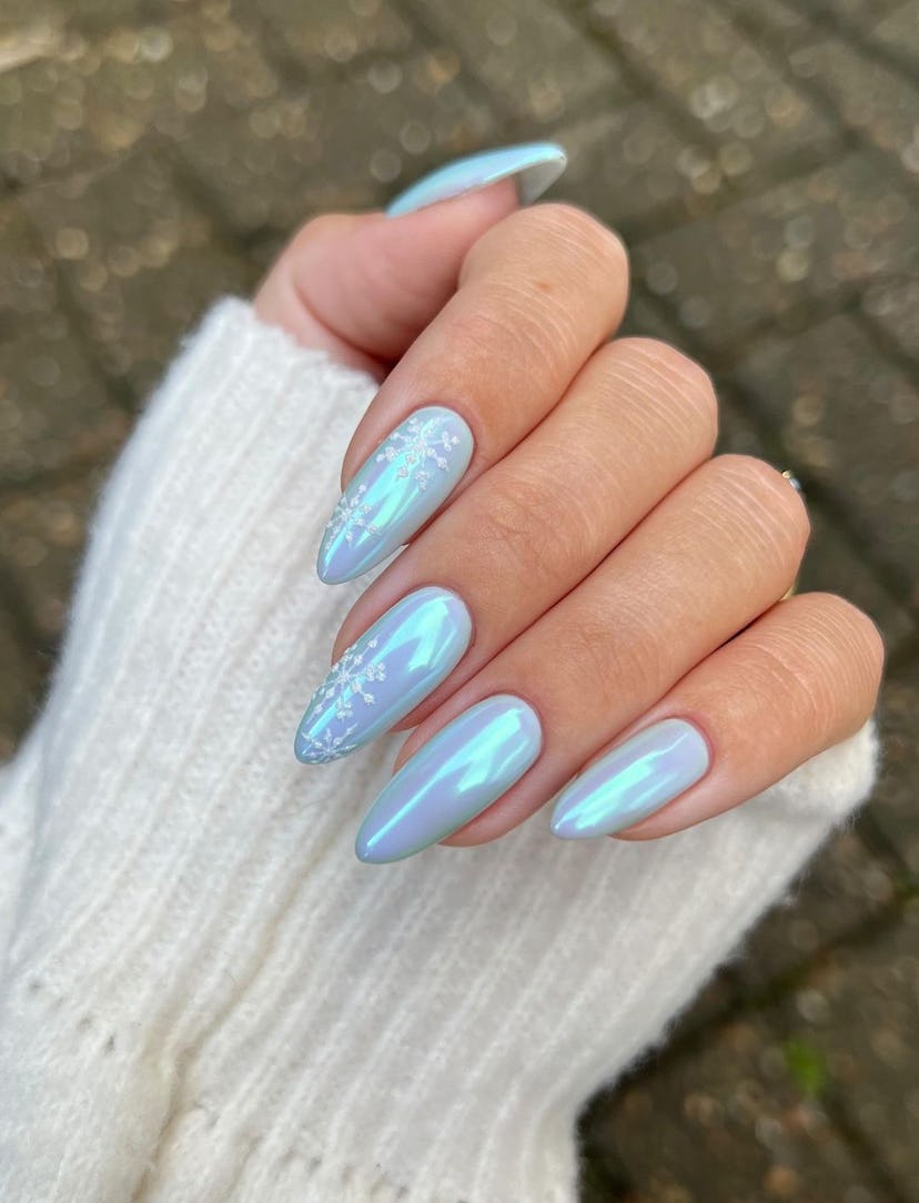 For a simple Christmas nail design for the 2023 holiday season, blue chrome nails with snowflake nai...