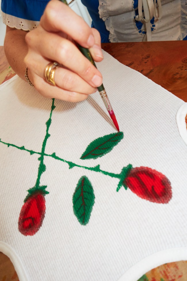A photo of Keely Murphy's hands painting roses onto paper.