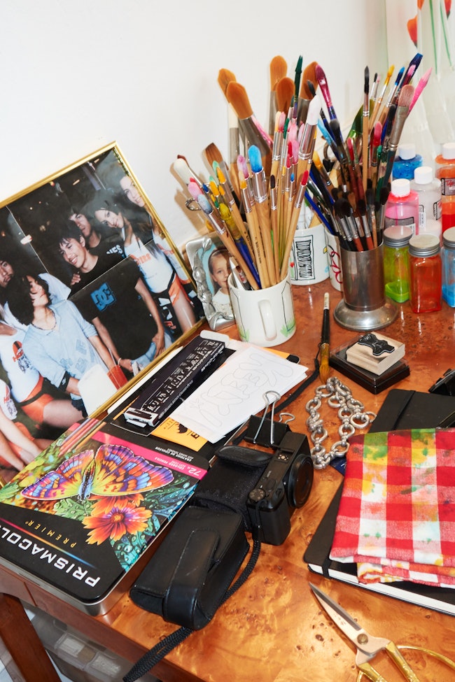 A photo of Keely Murphy's artist's desk populated with photos and buckets of paintbrushes. 