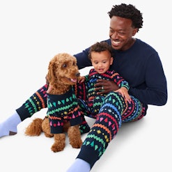 Dad, baby, and dog in matching Christmas pajamas